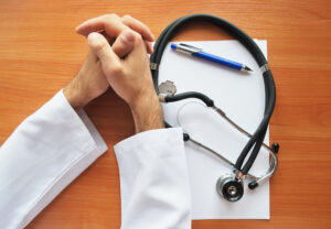 HandsOfDoctorWithStetoscopeAndWhipePaper