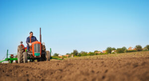 FarmerInOld-fashionedTractorSowingCropsAtField