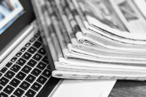 NewspapersAndLaptop.PileOfDailyPapersWithNewsOn