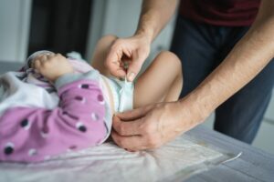 ManCaucasianFatherChangeDiapersToHisDaughterToddlerIn