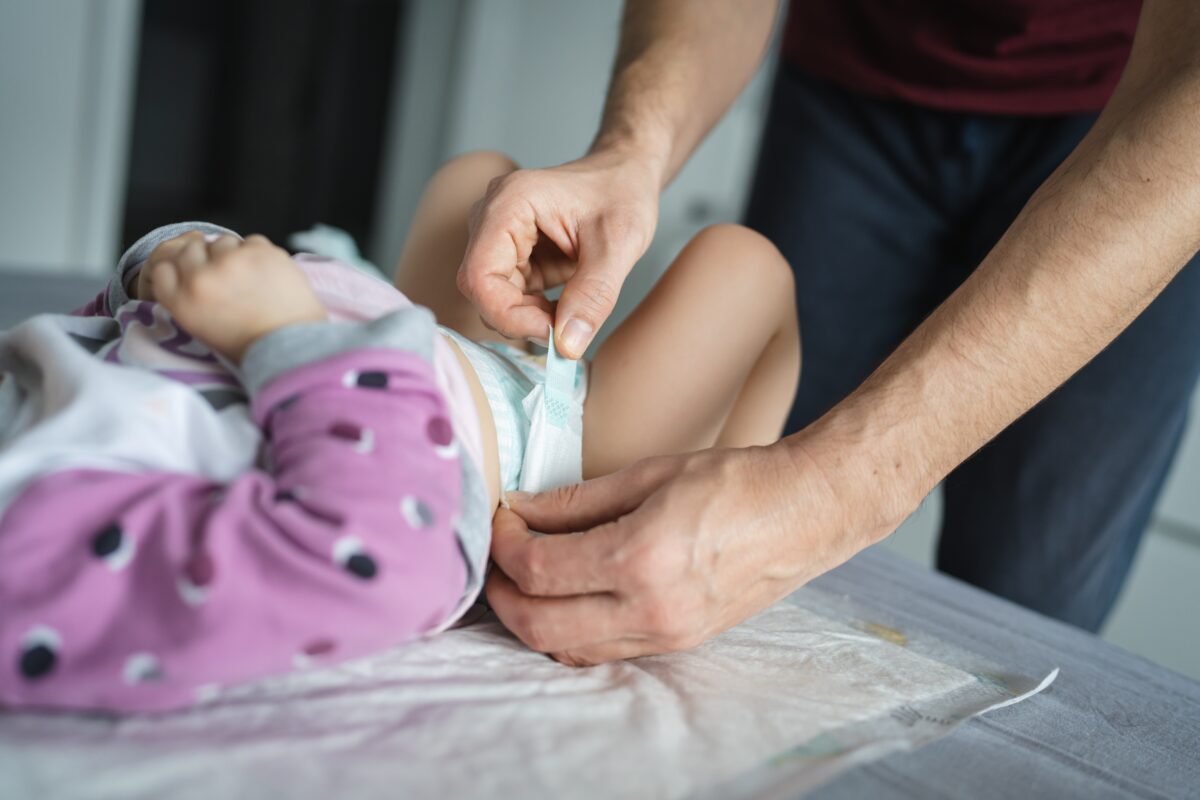 ManCaucasianFatherChangeDiapersToHisDaughterToddlerIn