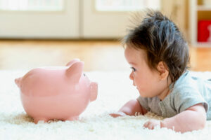 BabyBoyWithAPiggyBankInChildcareCostsOr