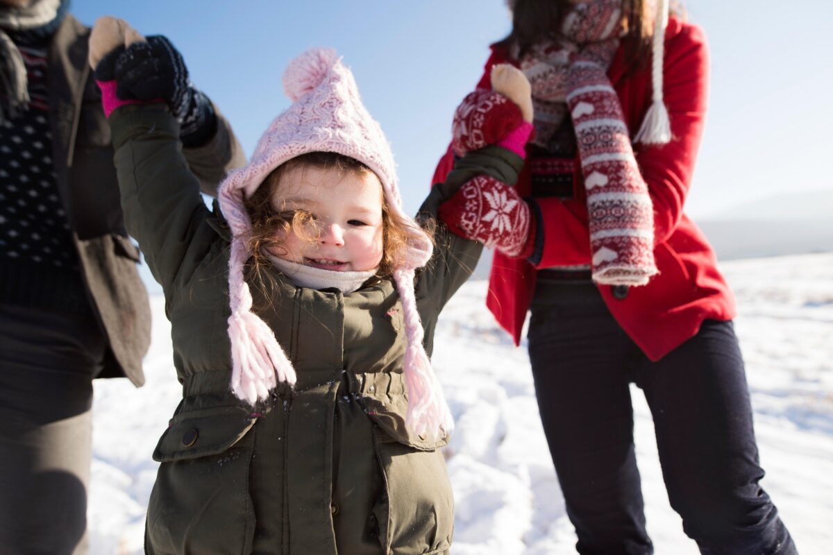 Unrecognizable-parents-with-their-daughter-on-a-walk-in-winter