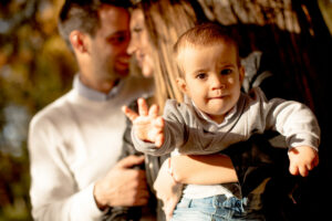 Happy-young-parents-with-baby-boy-in-autumn-park