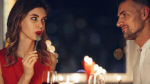 688z387-young-woman-eating-flirting-with-her-man-while-have-romantic-dinner